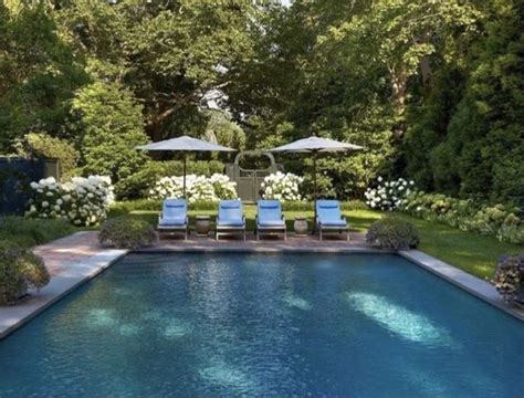 An Outdoor Pool With Lawn Chairs And Umbrellas Next To The Swimming