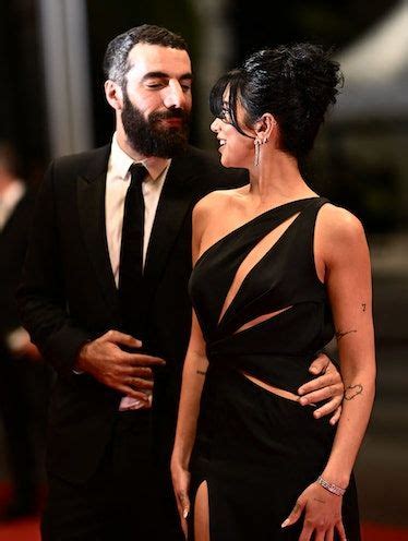 A Man And Woman Standing Next To Each Other In Front Of A Red Carpeted Area