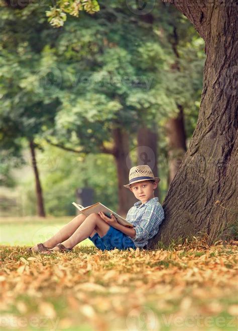 Boy With Book Sitting Under Big Tree In Park 942336 Stock Photo At Vecteezy