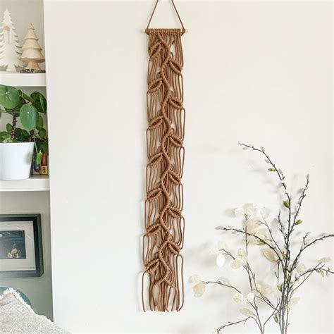 A Wall Hanging Made Out Of Rope Next To A Potted Plant And Vase With