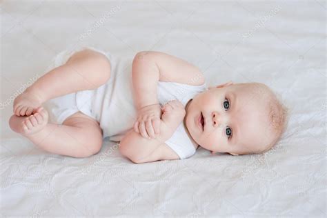 Retrato de bebé adorable niño acostado en la cama a su lado Foto de