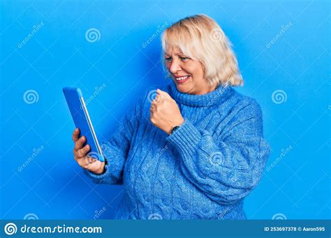 Middle Age Blonde Woman Using Touchpad Device Annoyed And Frustrated