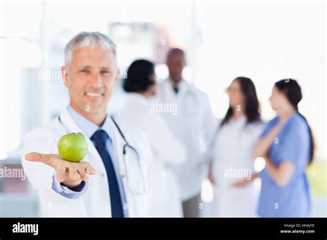 Smiling Mature Doctor Holding An Apple Stock Photo Alamy