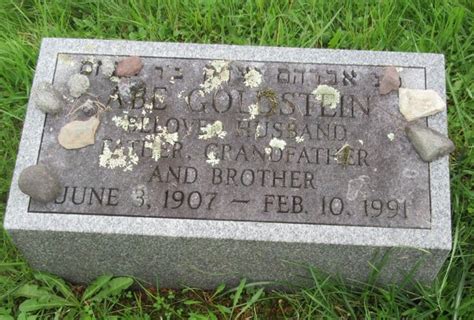 A Headstone On The Grass In Front Of Some Rocks