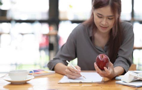 Jovem designer gráfico feminino asiático desenhando maçã em seu projeto