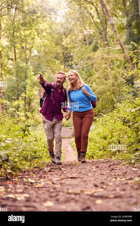 Mature Loving Couple In Countryside Hiking Along Path Through Forest