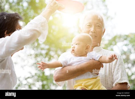 Grandparents Taking Care Of Baby Grandchild In Outdoor Park Asian