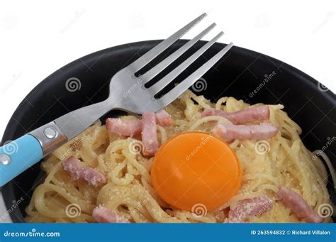 Plate Of Spaghetti Carbonara With An Egg Yolk And A Fork On A White