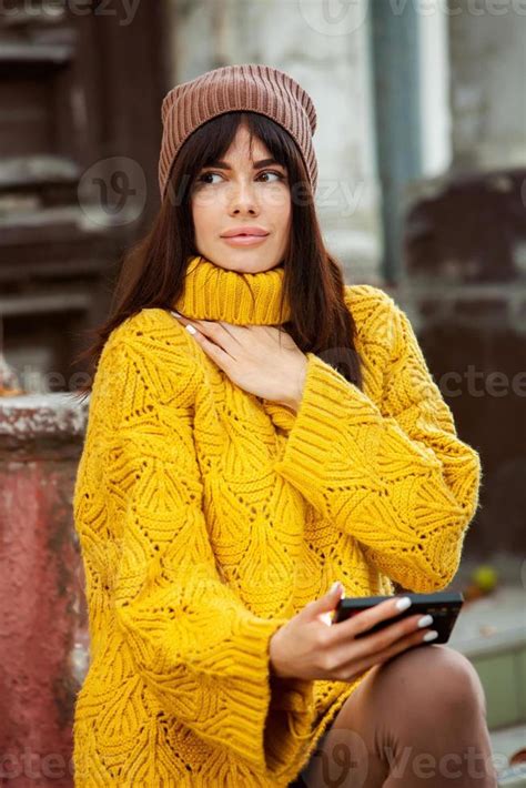 Beautiful European Brunette Dressed In A Yellow Woolen Sweater And Hat Outside The Beautiful