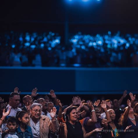 A Large Group Of People Standing In Front Of A Stage With Their Hands