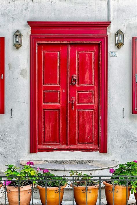 Red Doors And Windows With Potted Plants In Front Of Them On A White Wall