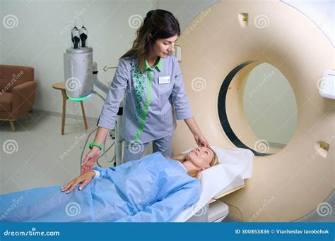 Focused Radiographer Preparing Female Client For Computed Tomography In