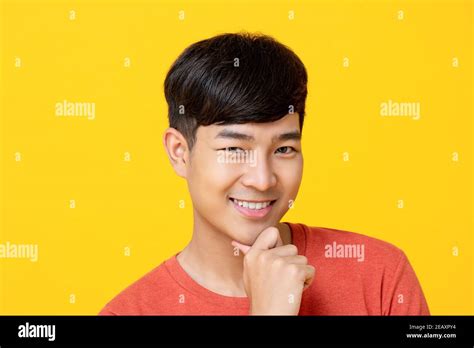 Handsome Young Asian Man Smiling With Hand On Chin Isolated On Colorful