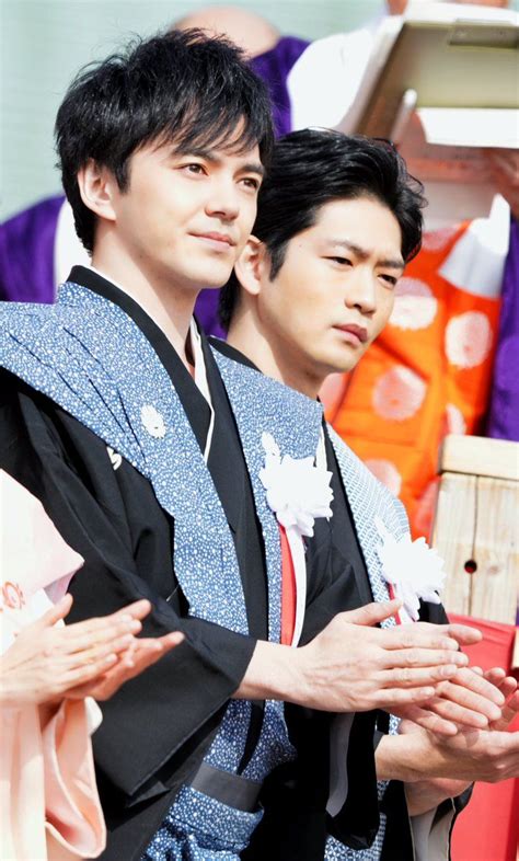 Two Men Dressed In Traditional Japanese Clothing Standing Next To Each