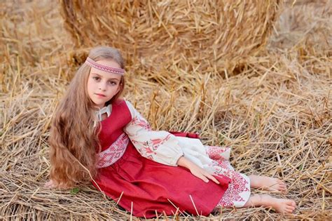 Une fille blonde aux grands yeux bruns dans un costume slave est assise sur un champ près d une