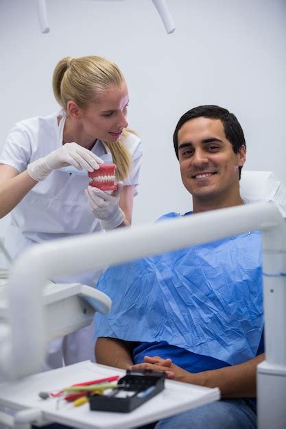 Dentista Mostrando O Conjunto De Dentes De Modelo Para O Paciente