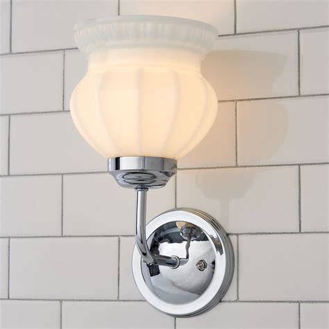 A Bathroom Light With A White Glass Shade On The Wall Next To A Brick Wall