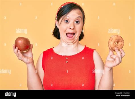 Brunette Woman With Down Syndrome Holding Red Apple And Donut Sitting