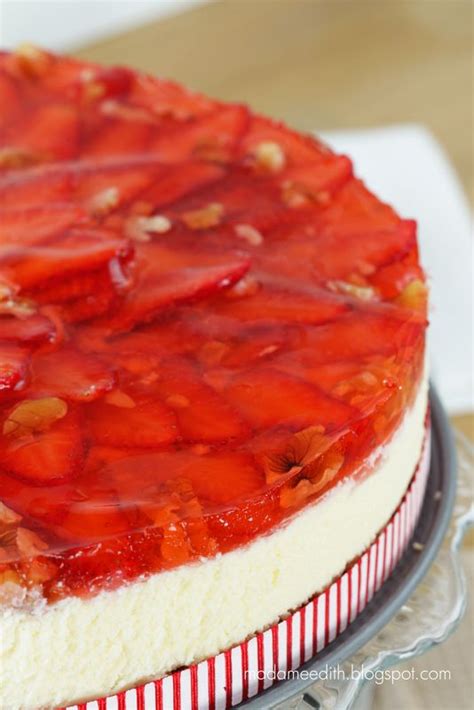 A Strawberry Cheesecake Is Sitting On A Glass Cake Plate With Red And