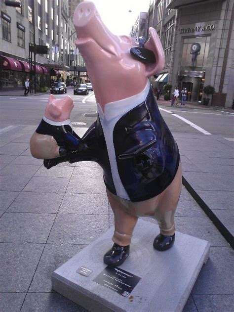 A Statue Of A Pig In Shorts On A City Street