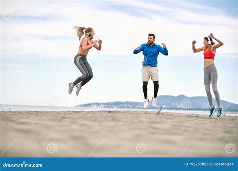 Gimnasios Saltando Y Haciendo Ejercicio En La Playa Foto De Archivo