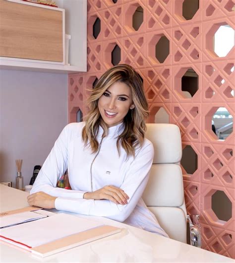 A Woman Sitting At A Desk In Front Of A Pink Wall With Geometric