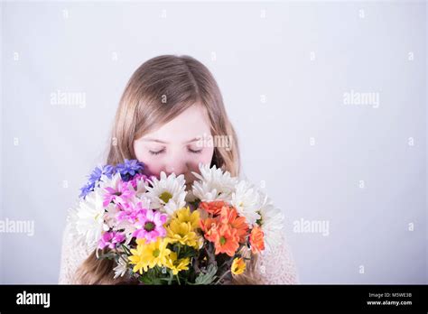 Twelve Year Old Girl With Long Dirty Blonde Hair Holding Colorful Bouquet Of Daisies Over Lower