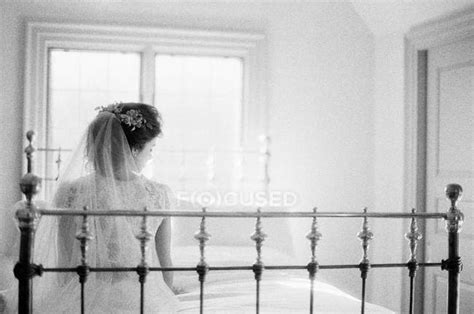 Woman In Wedding Dress Sitting On Bed Rear Monochromatic Stock