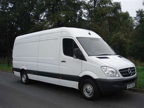 A White Van Is Parked On The Side Of The Road In Front Of Some Trees