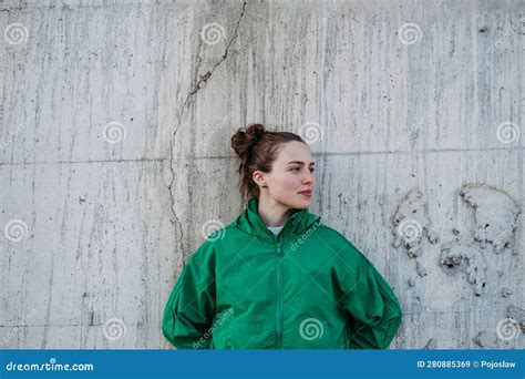 Waist Up Portrait Of Young City Woman Leaning Against A Concrete Wall