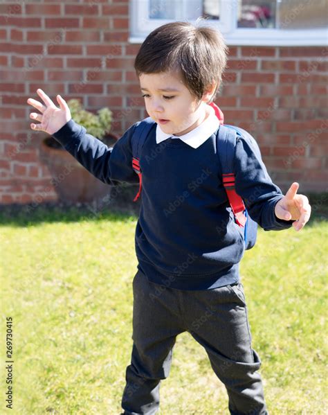 Happy little boy in school uniform playing at front garden in the sunny day, Active school kid ...