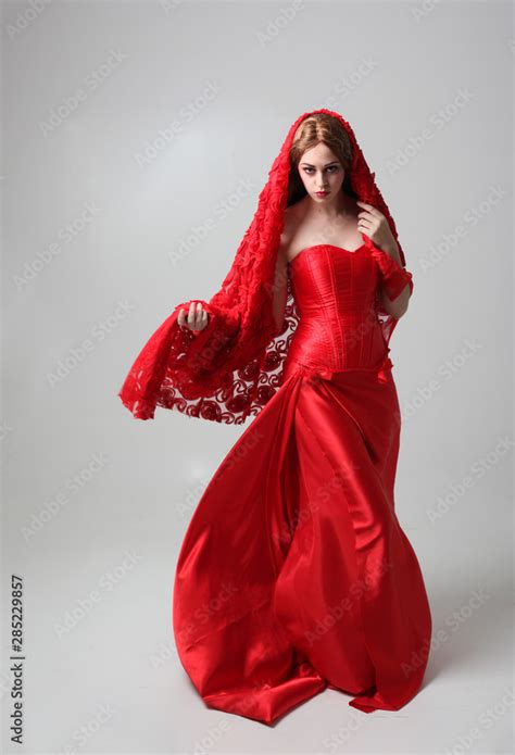 Full Length Portrait Of A Girl Wearing A Long Red Silk Gown Standing