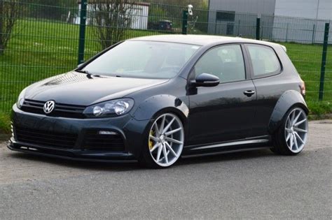 A Black Car Parked In Front Of A Fence