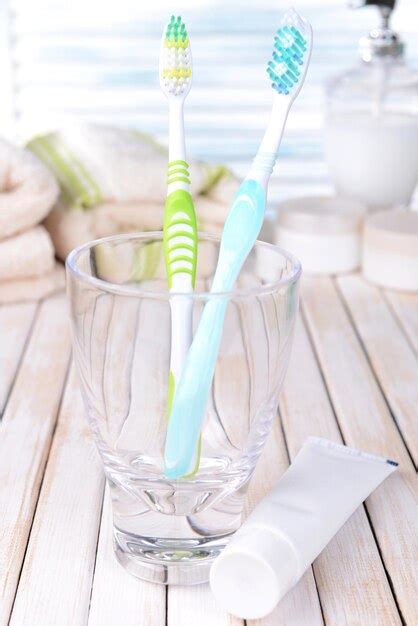 Premium Photo Toothbrushes In Glass On Table On Light Background