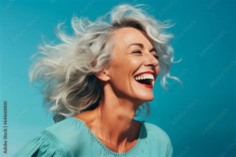 Close Up Portrait Photography Of A Happy Mature Woman Touching Her Hair Against A Turquoise Blue