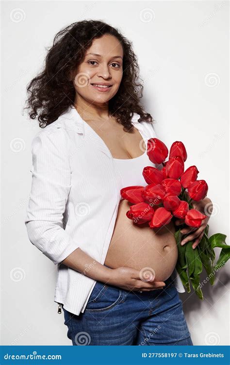 Multi Ethnic Pregnant Woman Posing Bare Belly With A Bouquet Of Red