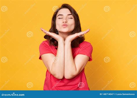 Close Up Portrait Of Pretty Caucasian Woman Makes Kiss With Lips Keeps Both Hands Under Chin