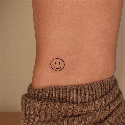 A Small Smiley Face Tattoo On The Side Of A Woman S Right Leg