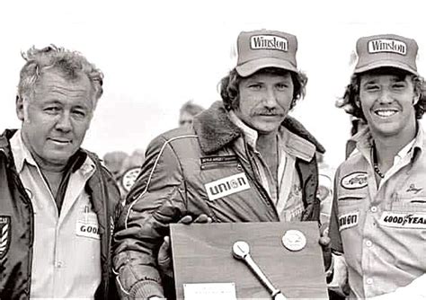 Three Men Standing Next To Each Other Holding A Plaque