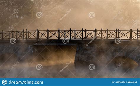 Concrete Bridge With Arches Over A Lake Covered With Fog Stock Photo