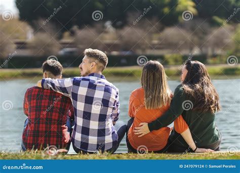 Pareja Gay Y Pareja Lesbiana Sentadas Y Abrazadas Al Borde De Un Lago Foto De Archivo Imagen