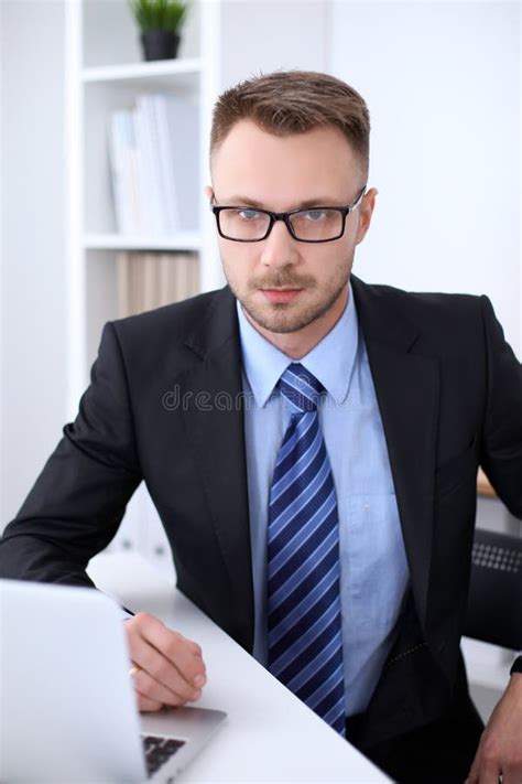 Portrait Of Businessman Sitting At The Desk In Office Workplace Stock