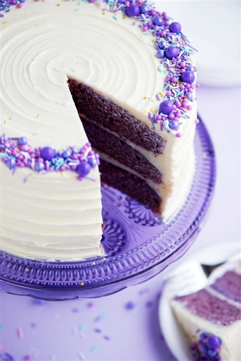 a cake with white frosting and purple sprinkles is on a plate