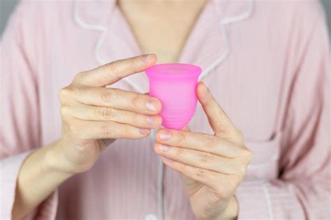 Closeup das mãos de uma mulher segurando um copo menstrual de silicone