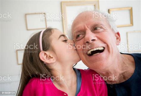 Loving Granddaughter Kissing Her Granddad On His Cheek And Grandfather