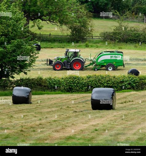 Hay Or Silage Making Farmer In Farm Tractor At Work In Rural Field