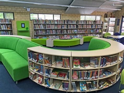 The Library Is Filled With Books And Green Couches