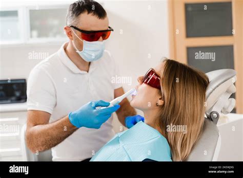 Dentist Treats And Removes Caries In Woman Patient Uv Illumination Of