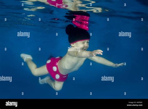 Niña vestida como Minnie Mouse nadando bajo el agua en la piscina