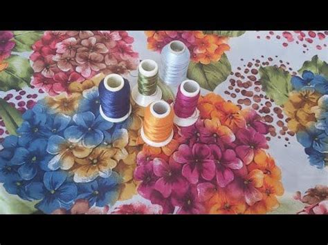 Several Spools Of Thread Sitting On Top Of A Flowered Tablecloth With